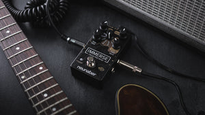 Neunaber Immerse pedal on the floor between a guitar and an amp