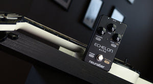 Neunaber Echelon Echo pedal on a table next to a guitar