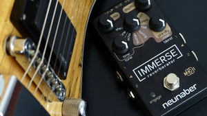 Neunaber Immerse Pedal on a table next to a guitar