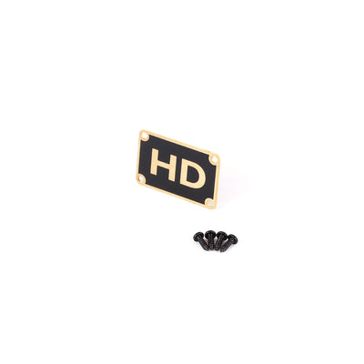 Golden badge that reads HD with four screws