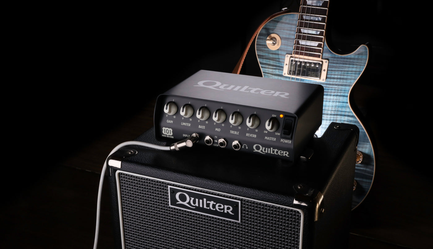 Quilter Labs Mini 101 Reverb Amplifier atop a Block Dock 10 TC cabinet with Gibson guitar in the background