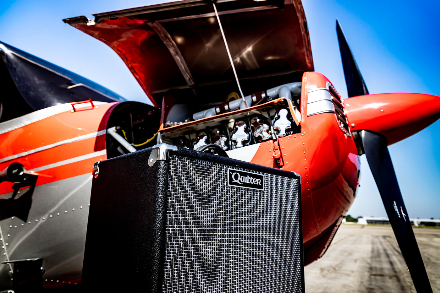 Quilter Aviator Cub Amplifier in front of an airplane with it's engine compartment open